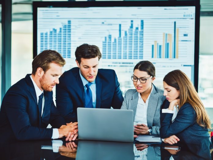 Business professionals analyzing digital financial charts in a modern office reflecting AI's impact on Wall Street jobs