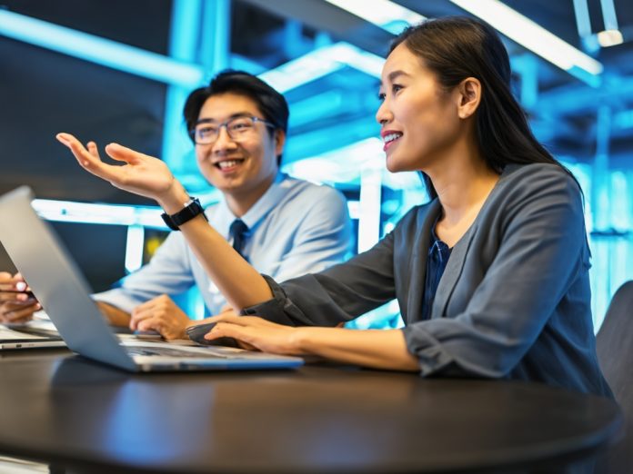 Two modern tech experts discussing plans in a futuristic lab