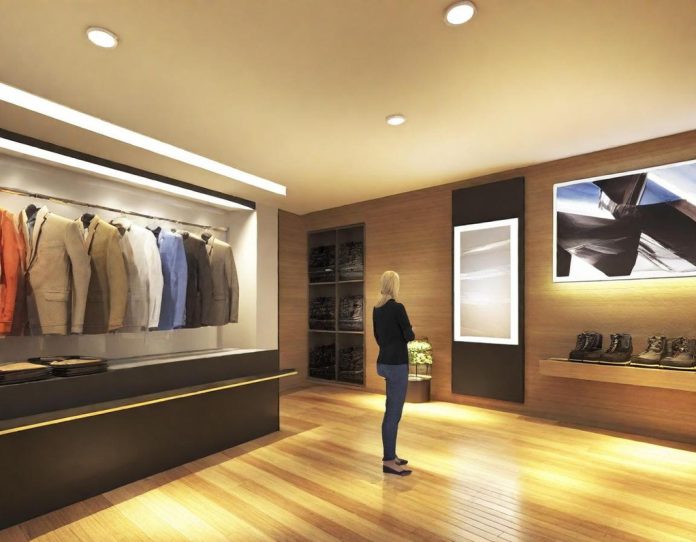 Customer using interactive digital display to customize virtual clothing in modern retail environment