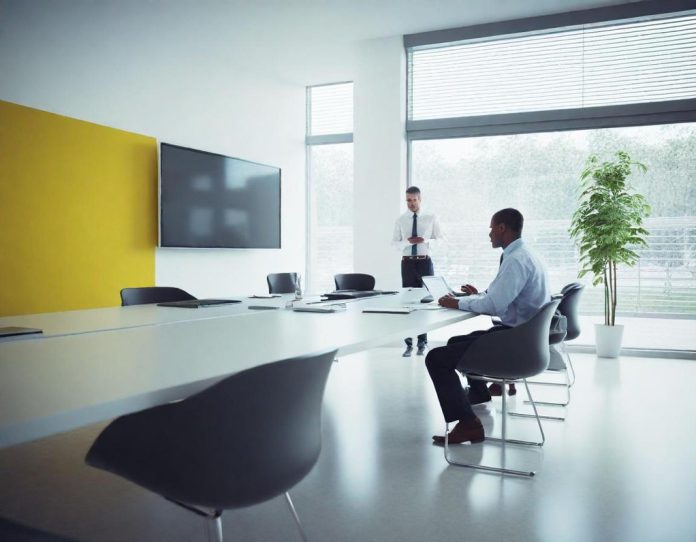 Diverse professionals collaborating in modern office setting with technology displays showing data visualizations