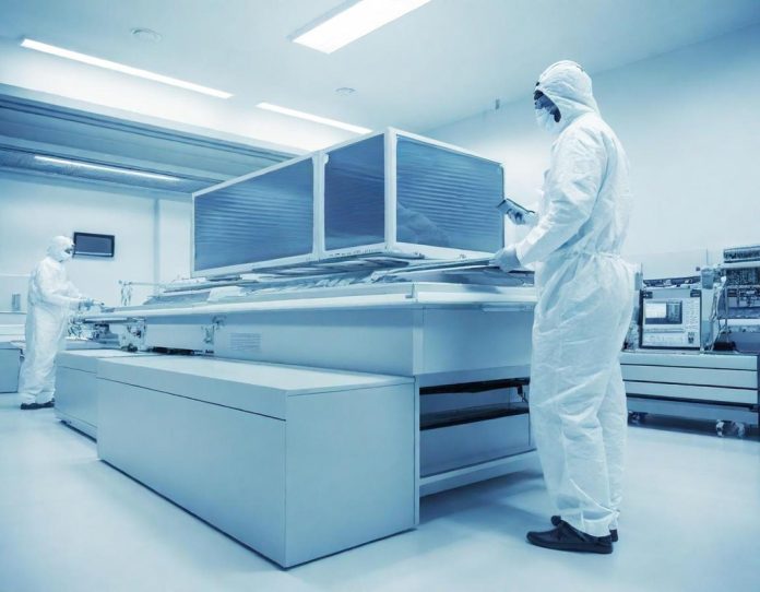 Engineers working in a semiconductor fabrication facility examining silicon wafers