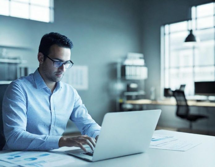 Professional analyzing hiring data trends on laptop in modern office setting