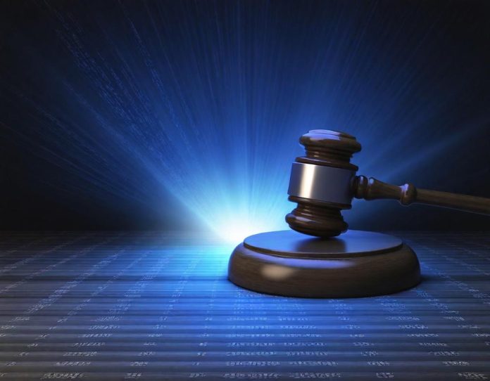 Courtroom gavel and legal documents beside computer screen showing digital code, representing technology legal battles