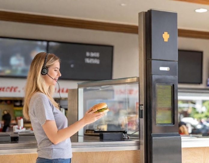 Fast-food employee using headset technology at drive-thru window during customer interaction